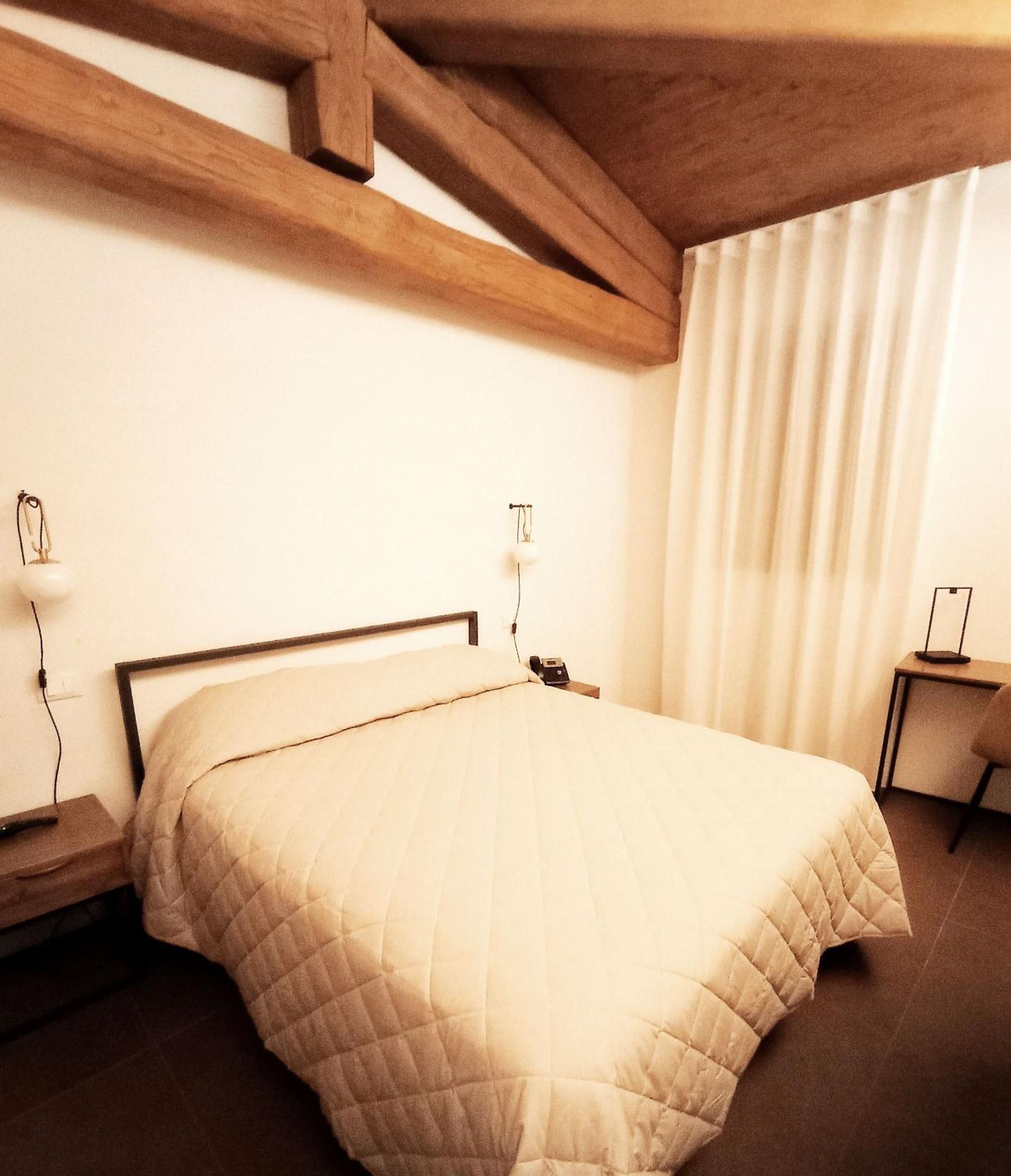 Une chambre à coucher avec un lit, des tables de chevet, une lampe et un téléphone.