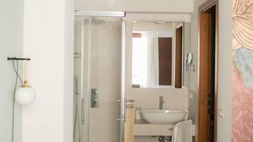 Un bagno moderno con cabina doccia in vetro, un lavabo con specchio e un asciugamano appeso al muro.