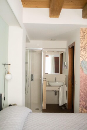 A modern bathroom with a glass shower enclosure, a sink with a mirror, and a towel hanging on the wall. - Locanda Le Logge (Urbisaglia)