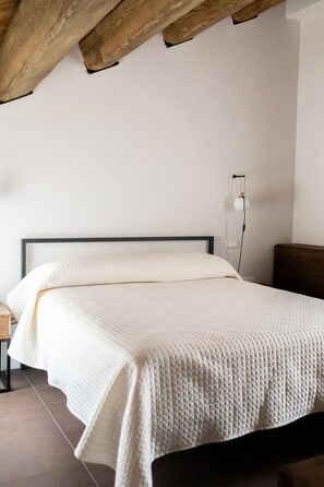 A bedroom with a bed, a nightstand, and a wall-mounted lamp. - Locanda Le Logge (Urbisaglia)