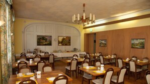 Un comedor con varias mesas y sillas, un reloj y cuadros en las paredes.