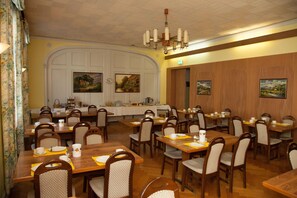 A dining area with multiple tables and chairs, a clock, and paintings on the walls. - Hotel Terminus Brugg (Brugg)