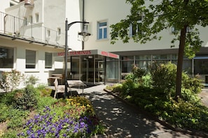 A hotel named 'HOTEL TERMINUS' with a modern facade, outdoor seating area, and a well-maintained garden. - Hotel Terminus Brugg (Brugg)