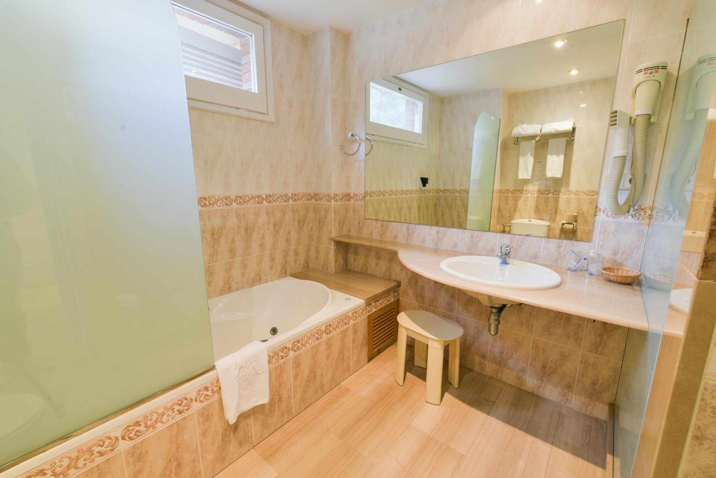 A bathroom with a bathtub, a sink, a vanity, and a mirror.