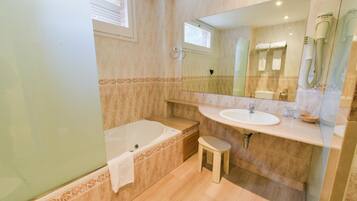 A bathroom with a bathtub, a sink, a vanity, and a mirror.