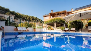 A swimming pool with lounge chairs, a pergola, and a building with a tiled roof in the background. - Hotel Robert (La Pobla de Claramunt)