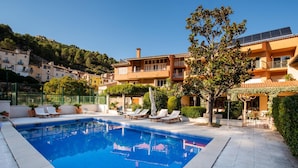 A swimming pool with lounge chairs, surrounded by buildings and greenery. - Hotel Robert (La Pobla de Claramunt)