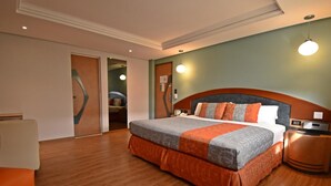 Ein Hotelzimmer mit einem großen Bett, einem Holznachttisch, einem Schreibtisch und einem Stuhl.