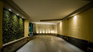 Ein Flur mit einer Steinwand, einer mit Pflanzen bepflanzten grünen Wand und einem gemusterten Boden.