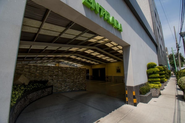 A building entrance with a covered walkway and a stone wall. - Hotel Catalina (Mexico City)