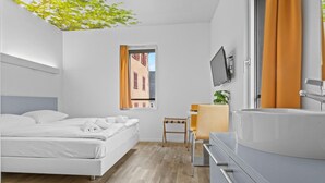 Una habitación de hotel moderna con cama, escritorio, televisor y baño.