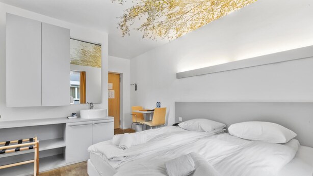 Un dormitorio moderno con una cama grande, un escritorio y un baño.