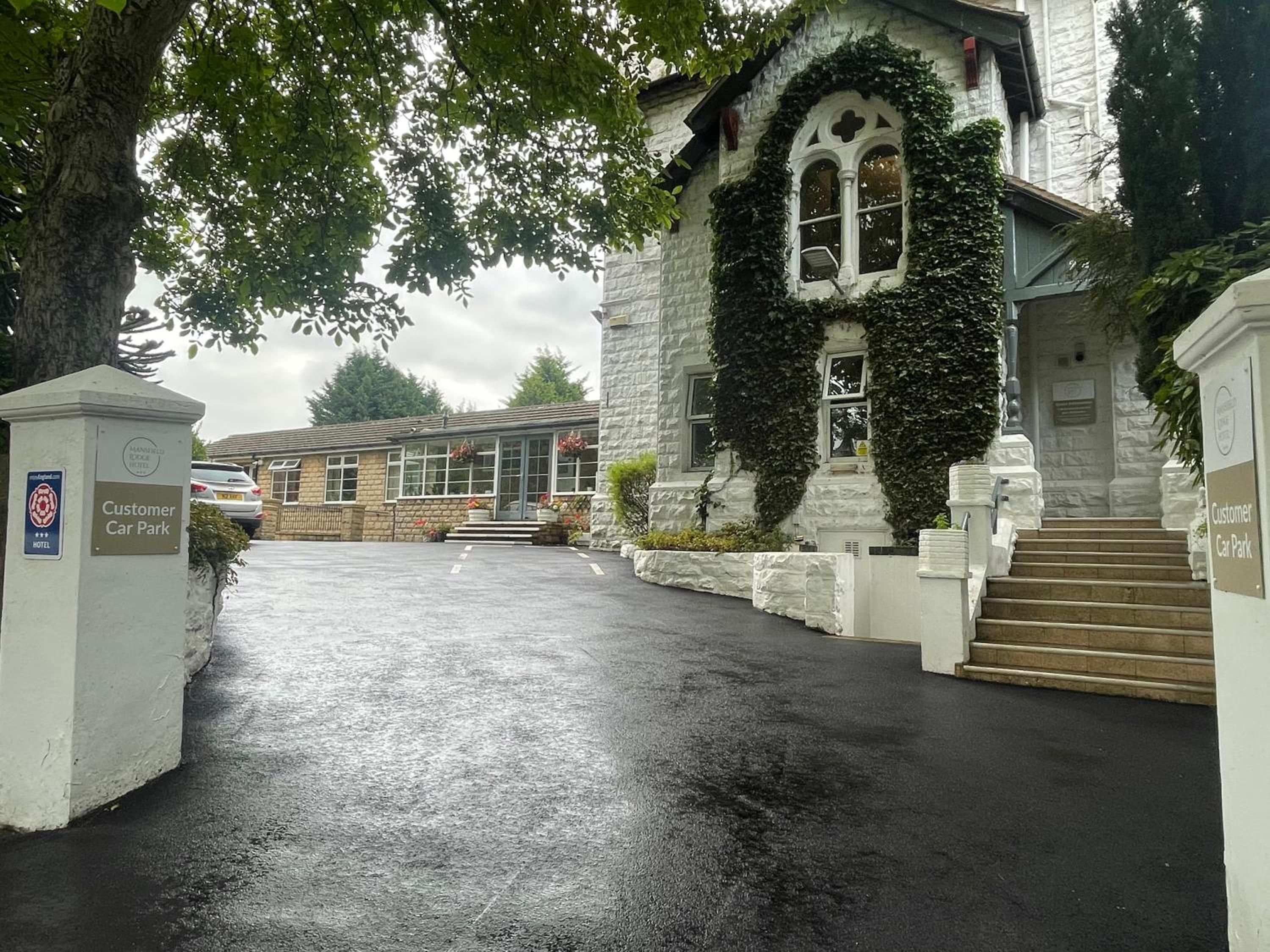 A building with a stone facade, a gated entrance, and a sign indicating a customer car park.