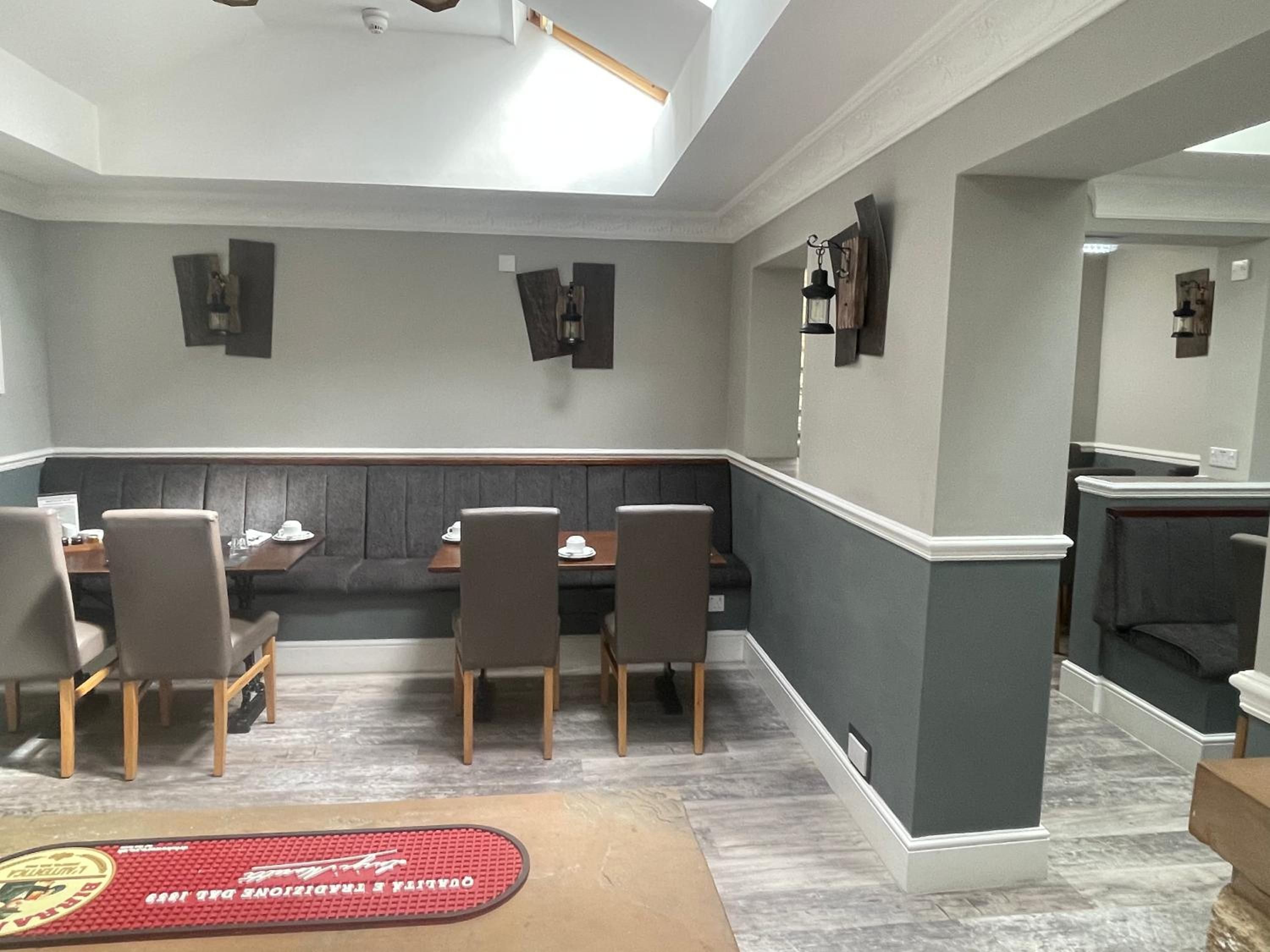 A dining area with a booth seating arrangement, a marble floor, and a red doormat with a logo.
