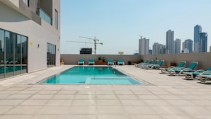 Ein Poolbereich auf dem Dach mit einer Skyline im Hintergrund.