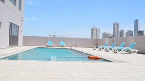 Ein Pool auf dem Dach mit klarem, blauem Wasser, umgeben von weißen Liegestühlen und einem Rettungsring.