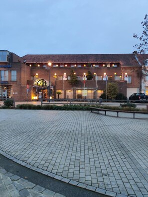A hotel with a brick facade, a covered entrance, and a paved courtyard. - De Basiliek (Edegem)