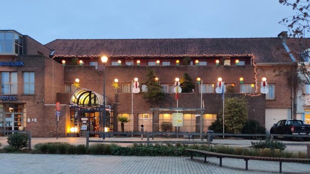 A hotel with a brick facade, a covered entrance, and a paved courtyard. - De Basiliek (Edegem)