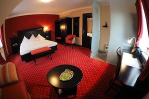 Una camera d'albergo con un letto, una scrivania, una sedia e un tavolino con vassoio.