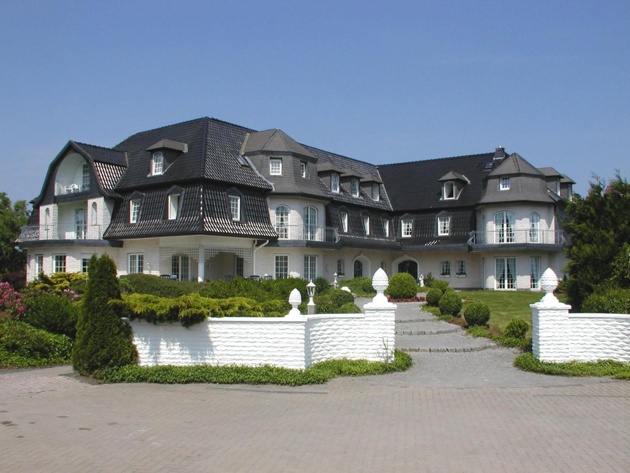 Un grand immeuble à plusieurs étages, doté d’une façade symétrique, de nombreuses fenêtres et d’une entrée centrale.