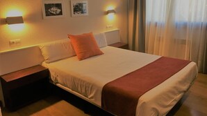 A hotel room with a bed, bedside tables, wall-mounted lights, and curtains. - Hotel Elorrio (Elorrio)