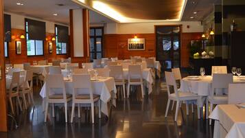 A restaurant with multiple tables and chairs, a wooden interior, and a view of the outside.