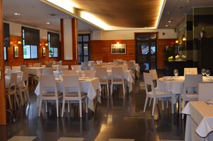 A restaurant with multiple tables and chairs, a wooden interior, and a view of the outside.