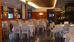 A restaurant with multiple tables and chairs, a wooden interior, and a view of the outside. - Hotel Elorrio (Elorrio)