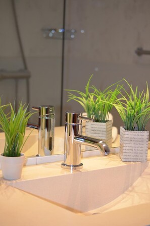 A bathroom with a modern sink, two chrome faucets, and three potted plants. - Hotel Elorrio (Elorrio)