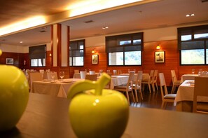 Un restaurante con varias mesas y sillas, ventanas amplias e iluminación empotrada en el techo.