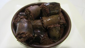 A bowl of chocolate dessert with a glossy coating.