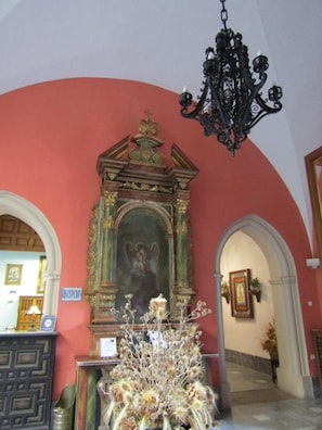 An interior with a reception desk, a chandelier, and a religious icon.