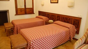 A room with two beds, a bench, a telephone, and a radiator.