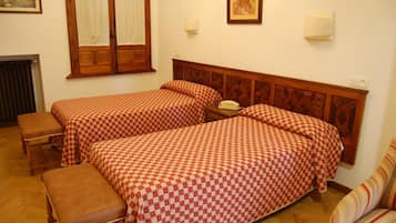 Quarto com duas camas, um banco, telefone e radiador.