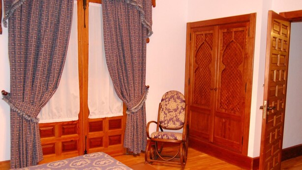 A room with a bed, a chair, and a wooden door.