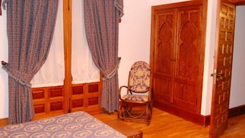 Ein Zimmer mit einem Bett, einem Sessel und einer Holztür.