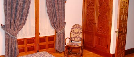Una habitación con cama, una silla y una puerta de madera.