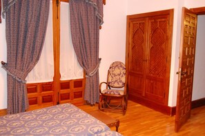 Una habitación con cama, una silla y una puerta de madera.