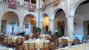 A spacious courtyard with multiple tables set for dining, surrounded by arches and columns. - Hospederia Del Real Monasterio (Guadalupe)