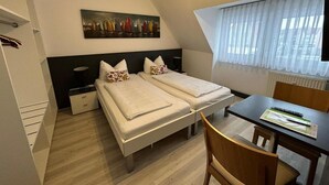 Een hotelkamer met twee bedden, een bureau en een stoel.