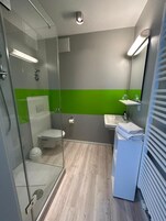 Un baño moderno con cabina de ducha de vidrio, inodoro, lavabo y espejo.