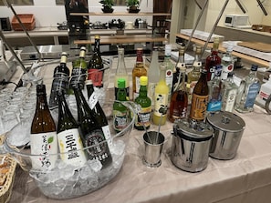 A variety of alcohol bottles on a table with ice, surrounded by kitchen appliances and a microwave. - Kuretake Inn Premium Tajimi Ekimae (Tajimi)