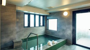 A modern bathroom with a large bathtub, a shower area, and a window providing natural light. - Kuretake Inn Premium Tajimi Ekimae (Tajimi)
