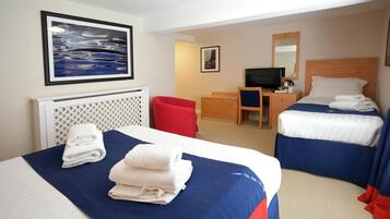 A hotel room with two beds, a desk, a television, and artwork on the walls.