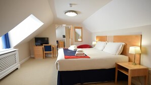 A hotel room with a bed, a desk, a television, and a window. - Royal Southern Yacht Club (Southampton)