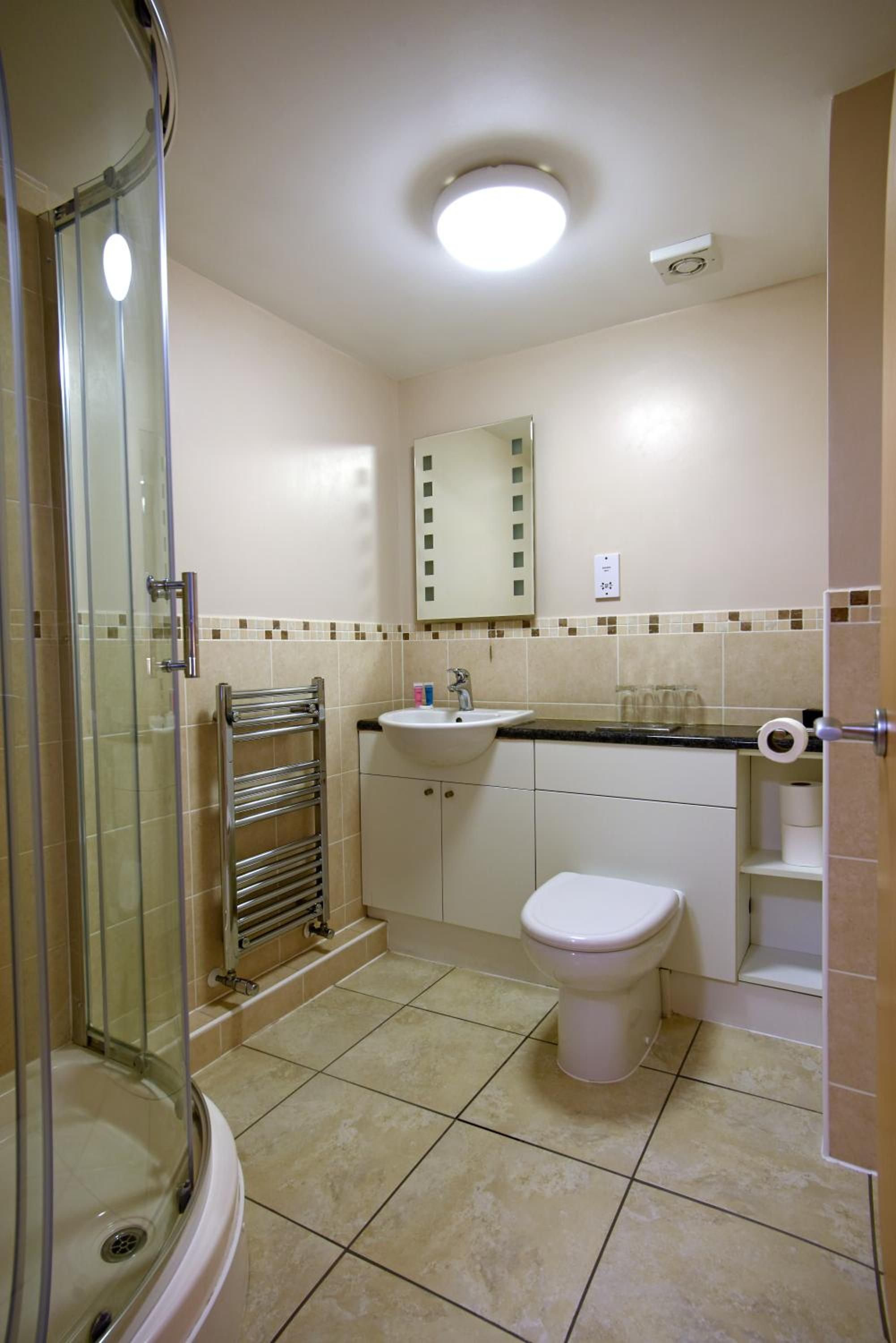 A bathroom with a glass shower enclosure, a sink, a toilet, and a mirror.