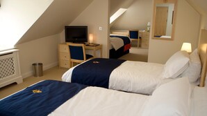 A hotel room with two beds, a desk, a television, and a mirror. - Royal Southern Yacht Club (Southampton)