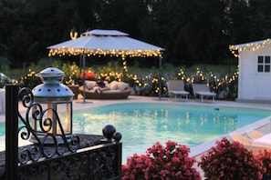 A swimming pool with a decorative lantern, a covered seating area with string lights, and a small building. - Villa Belvedere 1849 (Misano di Gera d'Adda)