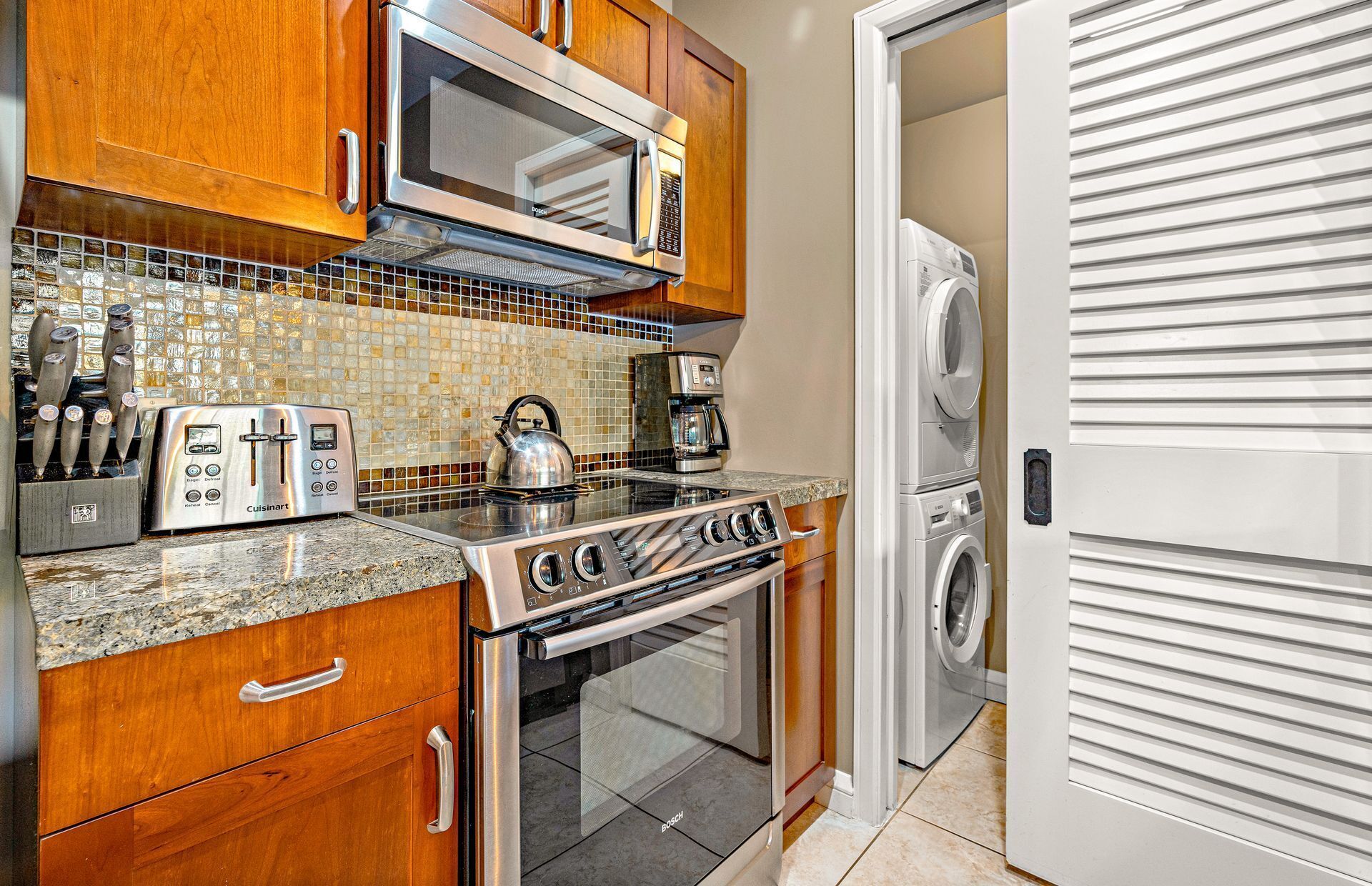 A kitchen with a Bosch microwave, toaster, kettle, and a washing machine.