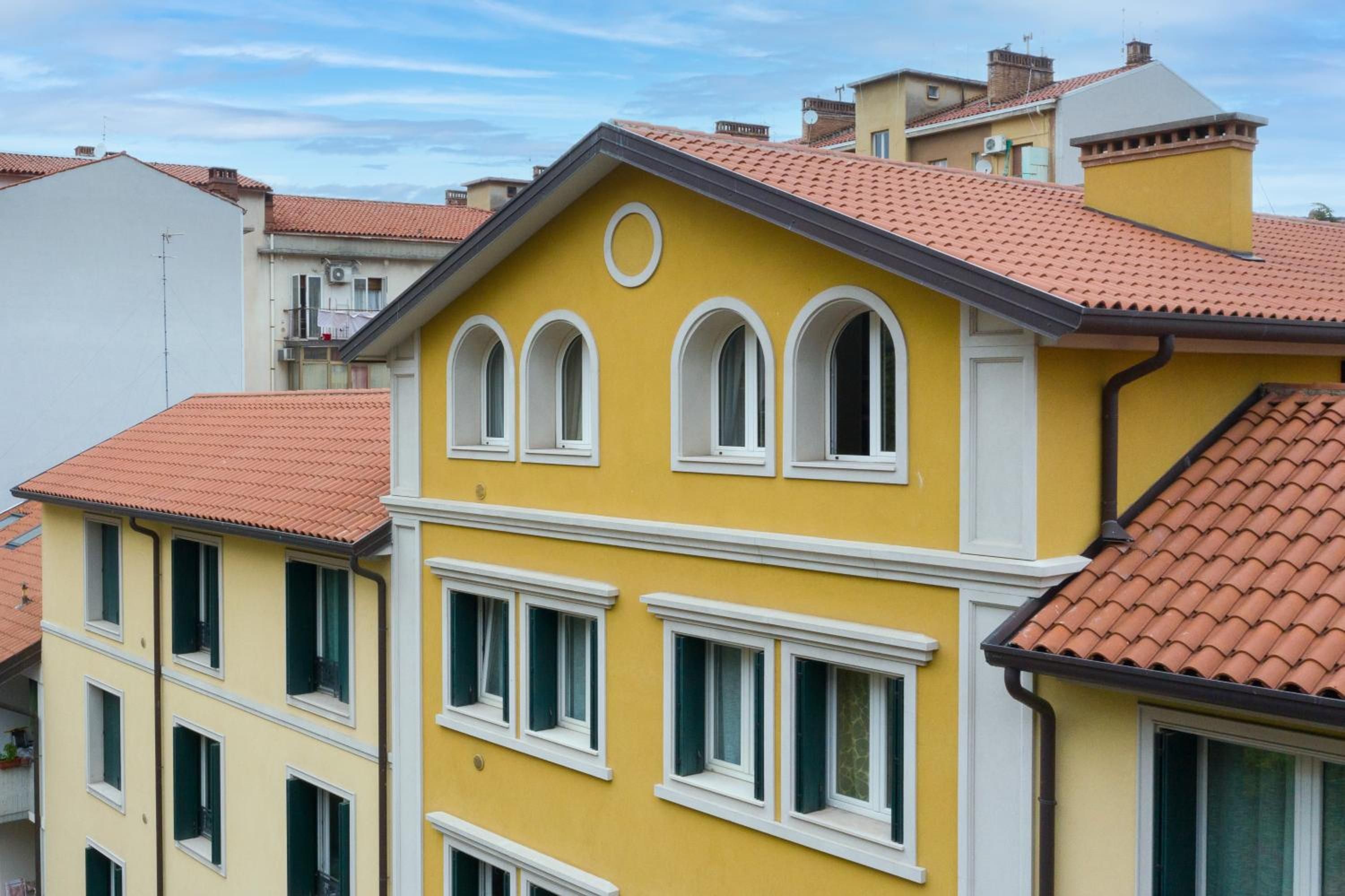 A yellow building with a red-tiled roof, multiple windows, and a white trim.